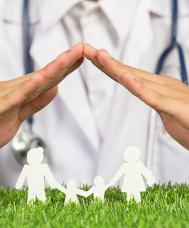 close up picture of doctor's hands posting symbol of home above family member model