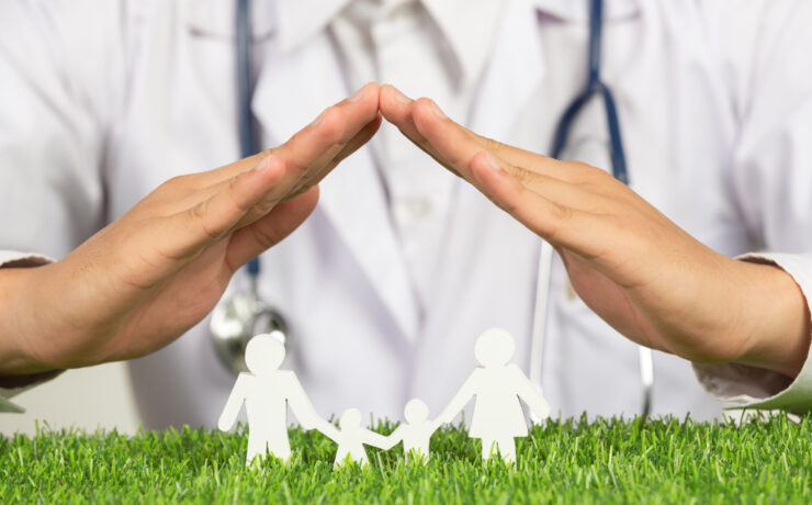 close up picture of doctor's hands posting symbol of home above family member model