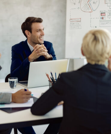Group of happy colleagues talking while having business meeting in the office.